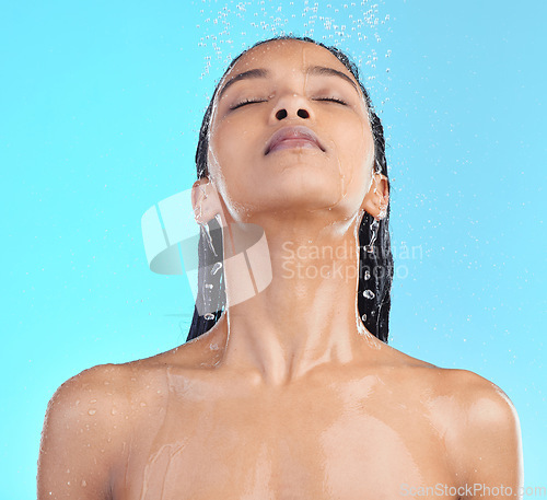 Image of Shower, woman and hair in studio for cleaning, wellness and grooming on blue background. Shower, hair care and black woman relax in water splash, beauty and skincare, hygiene and standing isolated