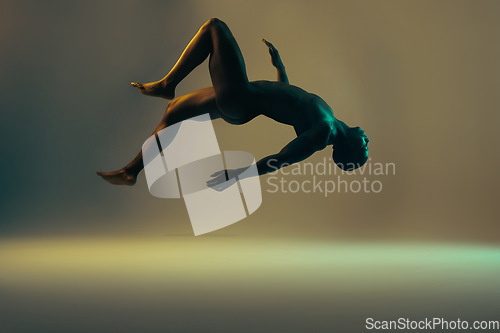 Image of Shadow, black man and nude model in a studio background for creative art with lights. Isolated, floating and young naked body of a african person in the air with light showing dark art deco glow