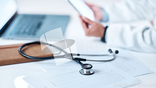 Image of Stethoscope, desk and documents with hands, tablet or research for doctor in hospital office. Healthcare clinic workspace, telehealth communication or tools for paperwork, notebook or laptop on table