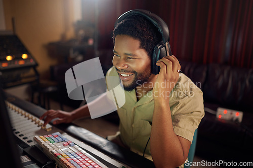 Image of Headphones, studio and male music producer working a album, song or audio with tech equipment. Happy, smile and black man radio presenter playing a playlist with technology in his creative workplace.