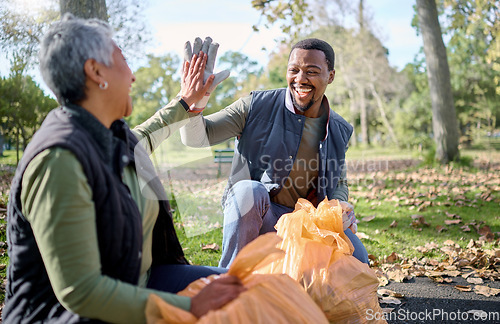 Image of High five, volunteer cleaning and people celebrate cleaning garbage, pollution or waste product for environment support. Community, NGO charity and eco friendly team help with nature plastic clean up