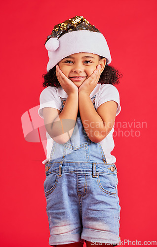 Image of Little girl, face and portrait smile for Christmas, celebration or surprise isolated on a red studio background. Happy child smiling in happiness with hands looking adorable for festive season gift