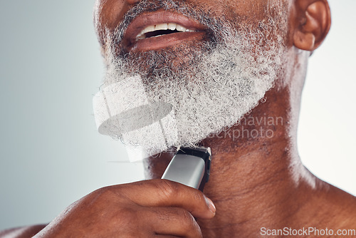 Image of Grooming, skincare and man shaving beard on face isolated on a grey studio background. Cleaning, smile and African senior model with a tool for facial hair removal, hygiene and routine on a backdrop