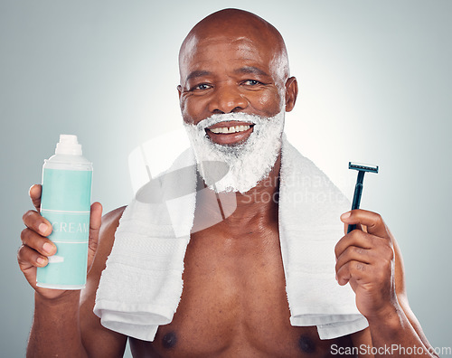 Image of Black man, beard and shaving with razor, cream or cosmetics for skincare, grooming or self care against gray studio background. Portrait of happy African American male with shave kit for clean facial