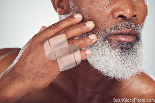 Image of Hand, beard and face with a senior black man grooming in studio on a gray background for beauty or skincare. Skin, hygiene and cosmetics with a mature male indoor to promote facial hair maintenance