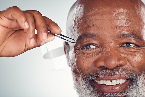 Image of Grooming, smile and black man with tweezers for hair removal isolated on grey studio background. Cleaning, routine and senior African person with a product on face for shaping eyebrows on a backdrop