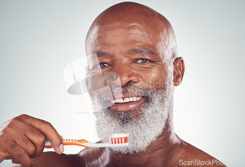 Image of Dental, senior man portrait and toothbrush for oral hygiene in a studio for wellness and health. Gray background, happy face and elderly person with teeth cleaning product and toothpaste product