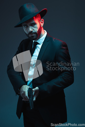 Image of Man, suit or holding gun on dark studio background in secret spy, isolated mafia leadership or crime lord security. Model, gangster or hitman with pistol in style, formal or fashion clothes aesthetic