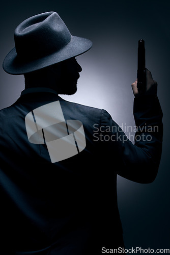 Image of Gangster, silhouette or holding gun on studio background in secret spy, isolated mafia leadership or crime security. Model, man or dark hitman and weapon suit, fashion clothes or bodyguard aesthetic