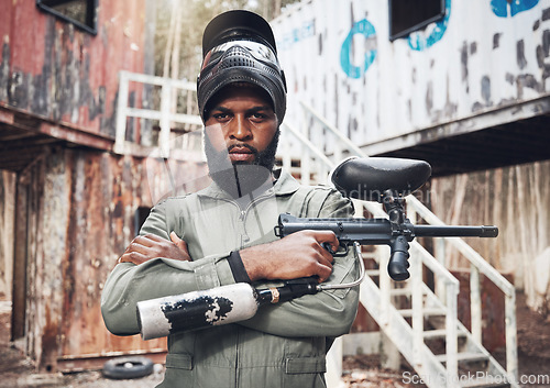 Image of Arms crossed, portrait and black man with a paintball gun for fitness, training or a game. Exercise, focus and serious African player with a rifle for action, military work and outdoor competition