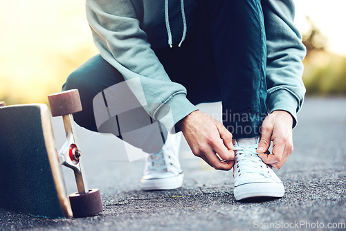 Image of Hands, skater and man tie shoes on street to start fitness, training or workout. Sports, skateboarding and male with skateboard, tying sneaker laces on road and getting ready for exercise outdoors.