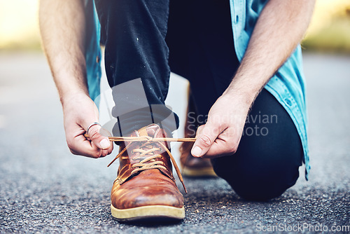 Image of Hands, road and man tie shoes on street to start fitness walk on holiday or vacation outdoors. Travel, wellness and male traveller tying footwear laces and getting ready for walking, journey or trek.