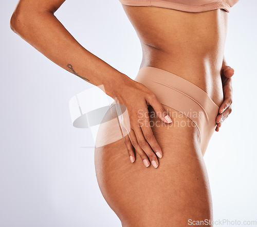 Image of Stretch marks, buttocks and underwear with a model black woman in studio on a gray background for body positivity. Cellulite, real and natural with a female posing in lingerie from the side