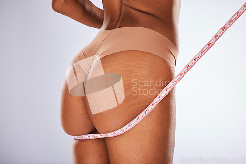 Image of Measuring tape, woman and butt in studio for weight loss, diet and health progress on grey background. Tape, size and girl model check, measure and slimming results while posing in underwear isolated