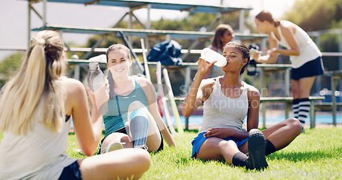 Image of Sport, outdoor and women relax with water bottle, hydration and rest, field hockey athlete take training break. Health, wellness and fitness with sports team, collaboration and drink after workout