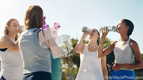 Image of Athletic woman, friends and drinking water for hydration during sports workout, training or practice together outside. Group of sporty women staying hydrated for healthy sport exercise in nature