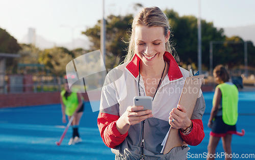 Image of Hockey, trainer and phone of woman at a stadium for training, workout and fitness while browsing at match. Sports, coach and female happy, smile and excited for app, message and online text outside