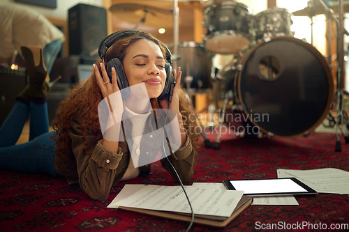 Image of Music, musician headphones and woman in studio streaming podcast, song or radio online. Relax, meditation and black female artist listening to audio recording while lying on floor with mockup tablet.