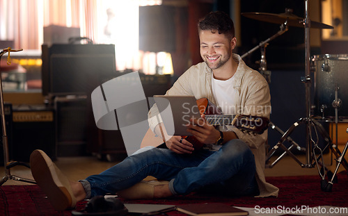 Image of Digital tablet, guitar and man in a recording studio for music production or acoustic performance. Musician, artist and happy male guitarist on a mobile device with a musical string instrument.