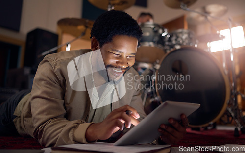 Image of Black man musician, tablet and technology in music studio for social media, lyrics research or internet browsing. Tech, digital touchscreen and male artist web scrolling or editing audio at night.