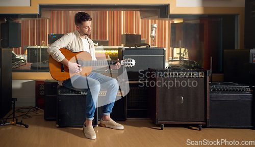 Image of Recording studio, acoustic and man playing the guitar for music production or practicing for a performance. Artist, guitarist and guy strumming the strings of a musical instrument for a sound track.