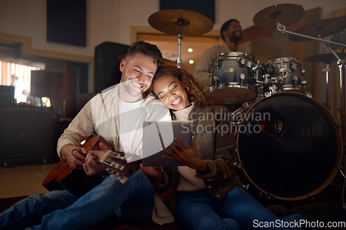 Image of Guitar, musician couple and tablet in studio for music production or social media. Musicians, diversity love and happy man and woman with acoustic instrument and technology for web scrolling at night