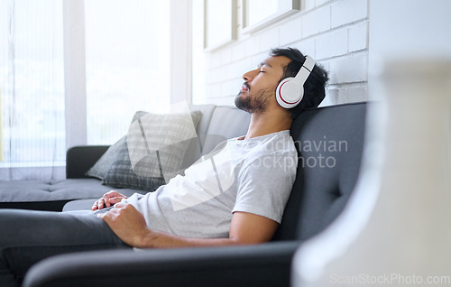 Image of Music, relax and man with headphones on sofa in home living room streaming radio or podcast. Meditation, technology and male on couch in lounge listening to peaceful song, audio or album in house.