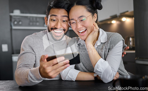 Image of Love, technology and couple with phone in home kitchen watching funny video online. Social media, wow and surprised asian man and woman with mobile streaming comic movie and laughing at night.