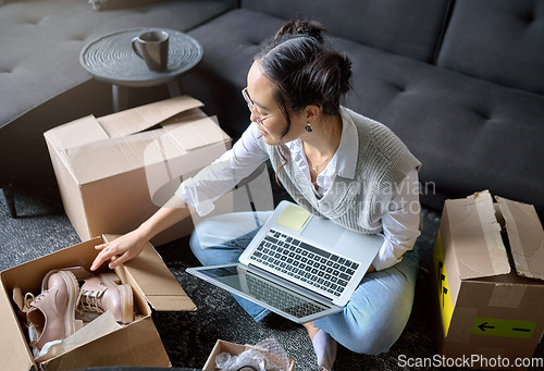 Image of Laptop, real estate and woman moving into new home while unboxing boxes with shoes. Relocation property, computer and top view of Asian female or house owner opening box of footwear in living room.