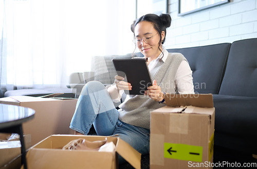 Image of Tablet, real estate and Asian woman moving into new home while planning or calculating mortgage online. Relocation boxes, technology and female property owner or remote worker in living room of house