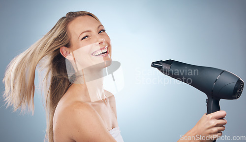 Image of Face, hair dryer and beauty portrait of woman in studio isolated on a gray background. Balayage, haircare and happy female model with hairdryer product for hairstyle, grooming or salon treatment.