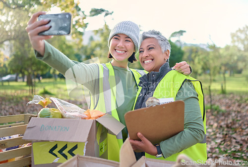 Image of Selfie, volunteer and donation with a woman charity or relief worker friends taking a picture together. Teamwork, community and photograph with female people carrying a box for humanitarian aid