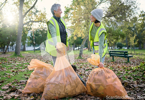 Image of Volunteer women, community service and cleaning park with garbage bag for a clean environment. Team talking and helping with trash for eco friendly lifestyle and recycling project outdoor in nature