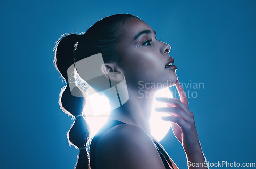 Image of Woman, beauty and profile of a model thinking in a studio with cosmetics and makeup. Young person, face hand touch and zen female with lighting and blue background isolated feeling relax and calm