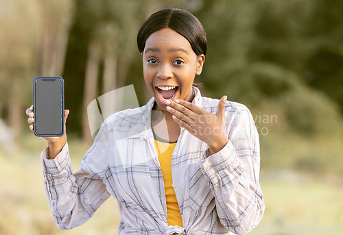 Image of Mockup, smartphone and black woman surprise in nature or park portrait for announcement or sale on mobile app. African person cellphone, mock up screen and wow on face for product placement in forest