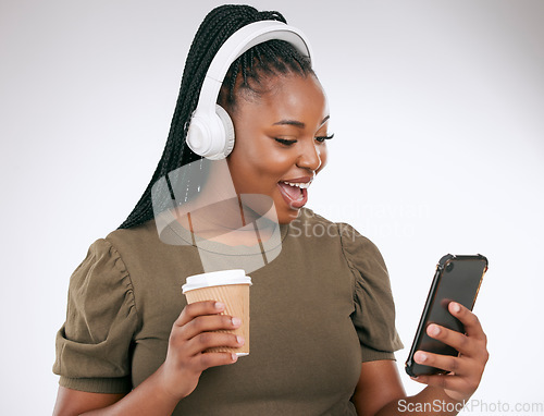 Image of Music, coffee and surprise with a black woman in studio on a gray background listening to the radio. Phone, social media or headphones and a young female streaming an audio playlist with a drink