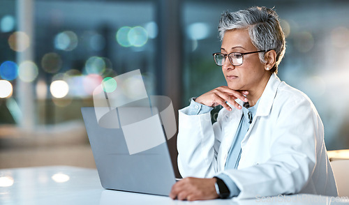 Image of Laptop, doctor and senior woman in hospital working late or overtime on email, telehealth or research. Bokeh, thinking and female medical physician reading healthcare information at night on computer