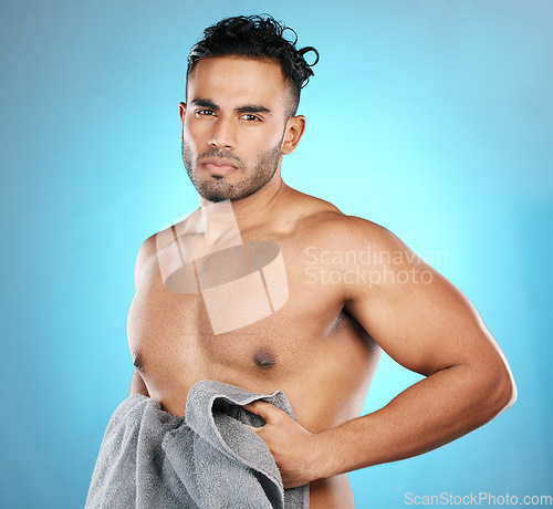 Image of Cleaning, towel and portrait of a man after a shower isolated on a blue background in a studio. Sexy, grooming and muscular model on a backdrop after washing body for hygiene, skincare and health