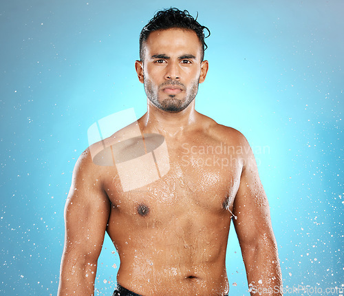 Image of Water splash, portrait and man in studio for skincare, wellness and grooming on blue background. Cleaning, beauty and moisture by Mexican model relax with luxury, routine and body care while isolated