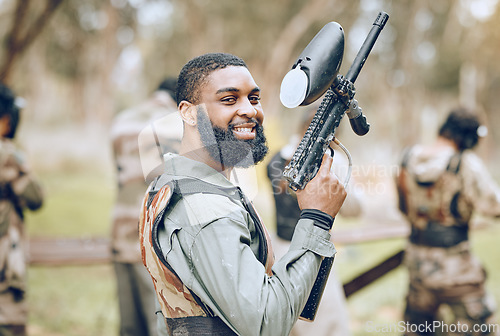 Image of Sports, paintball and portrait of black man with gun ready for game, arena match and shooting battle outdoors. Smile, adventure and male with weapon in camouflage, military clothes and action gear