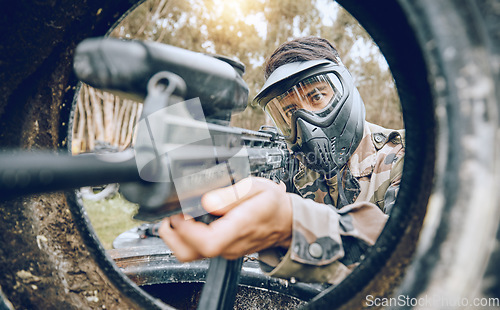 Image of Paintball, gun and man with focus, safety uniform and extreme sports for activity, gear and competition. Teamwork, male player or guy with camouflage, shooting paint rifle or military weapon for game