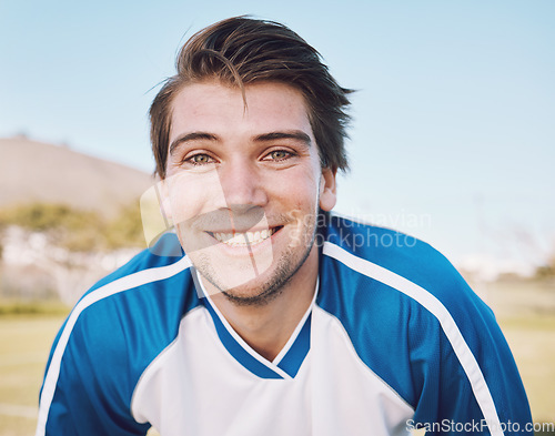 Image of Football player, portrait and smile on field for training, fitness and workout goals, mission and strategy on blue sky. Happy soccer athlete, person or man face for contest, game and outdoor sports