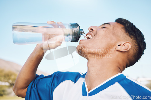 Image of Water, bottle and football or soccer player on sports field resting after match or competition on a sunny day. Man, athlete and sportsman refreshing during a game happy and smiling for fitness