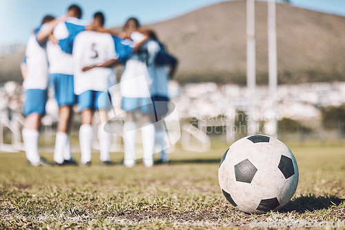 Image of Ball, sports field and team huddle, game and training for competition, fitness and exercise outdoor. Football, athletic group hug and planning for match, teamwork and wellness on grass, goal and zoom