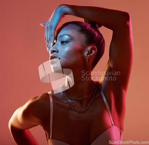 Image of Blue light, beauty and black woman profile feeling sexy and mystical with studio lights. Brown background, isolated and creative face glow of a female model with colorful lighting and glamour pose