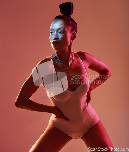 Image of Art, beauty and neon with a model black woman in studio posing in underwear on an orange background. Aesthetic, creative and fashion with an attractive young female standing on a kaleidoscope wall