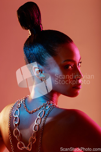 Image of Glamour, jewelry and portrait of a model in a studio with neon lights for aesthetic and cosmetics. Makeup, art and young woman with cosmetic beauty routine with accesories posing by orange background