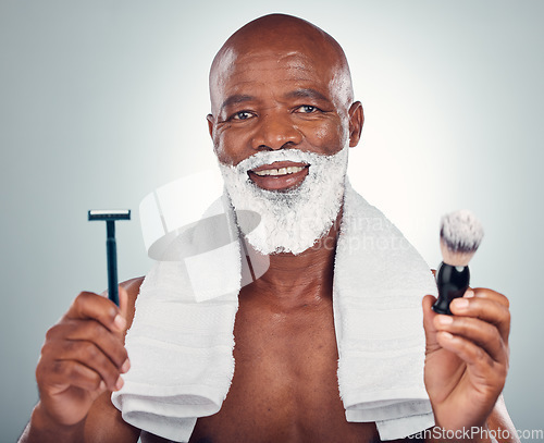 Image of Black man, beard and razor for shaving, skincare or cosmetic cream for grooming or self care against gray studio background. Portrait of happy African American male with shave kit for clean facial