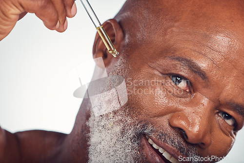 Image of Beauty oil cosmetic pipette by senior man doing skincare, grooming and self care routine isolated in studio white background. Serum, moisture and smooth or glow skin by old person or model