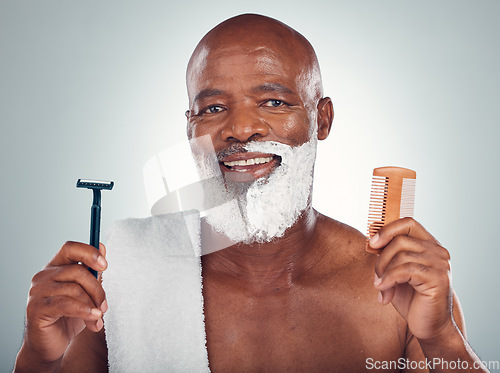 Image of Black man, portrait smile and beard for shaving with razor, cream and comb for skincare, grooming or self care on a gray studio background. Happy African American male with shave kit for clean facial